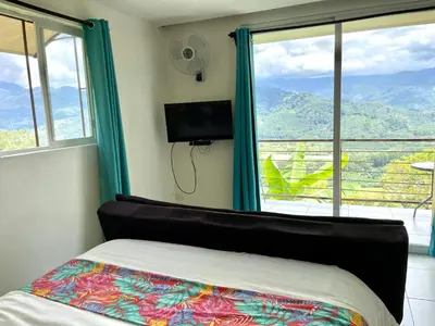 a bedroom with a bed and a tv and windows at Rinconcito Verde in Ujarrás