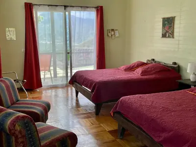 a room with two beds and a chair and a window at Rinconcito Verde in Ujarrás