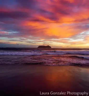 a sunset on the beach with a rock in the ocean at Hotel Verde Mar Direct Beach Access in Manuel Antonio