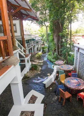 a patio with tables and chairs and trees at Hotel Verde Mar Direct Beach Access in Manuel Antonio