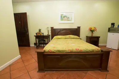 a bedroom with a wooden bed with a floral bedspread at Hotel Verde Mar Direct Beach Access in Manuel Antonio