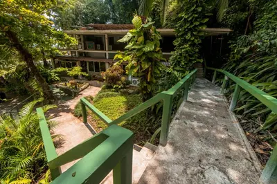a green fence in front of a house at Karahe Beach Hotel in Manuel Antonio