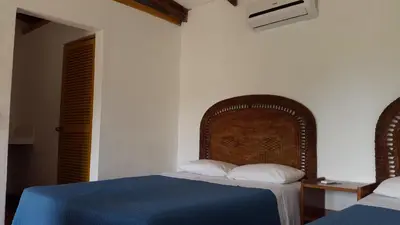a bedroom with a bed with a blue blanket and white pillows at Karahe Beach Hotel in Manuel Antonio