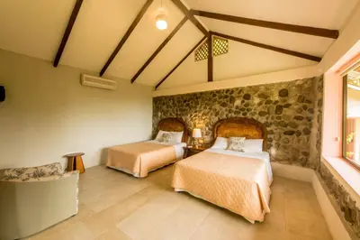 a bedroom with two beds and a stone wall at Karahe Beach Hotel in Manuel Antonio