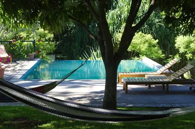 a hammock and a bench next to a pool at Guácima Escondida Hotel Boutique in Guácima