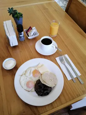 a table with a plate of breakfast food and a cup of coffee at Guácima Escondida Hotel Boutique in Guácima
