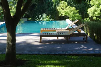 a bench sitting next to a pool with a tree at Guácima Escondida Hotel Boutique in Guácima