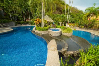 a swimming pool with blue water in a resort at Marbella 1E 3 bdr Ocean View in Los Suenos in Herradura