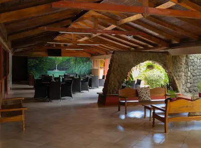 a lobby with tables and chairs and a stone wall at Hotel Las Espuelas, Bar & Restaurant in Liberia