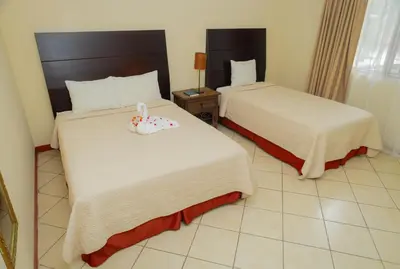 two beds in a hotel room with a toy on the bed at Hotel Las Espuelas, Bar & Restaurant in Liberia