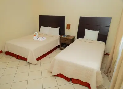two beds in a hotel room with a stuffed duck on the bed at Hotel Las Espuelas, Bar & Restaurant in Liberia