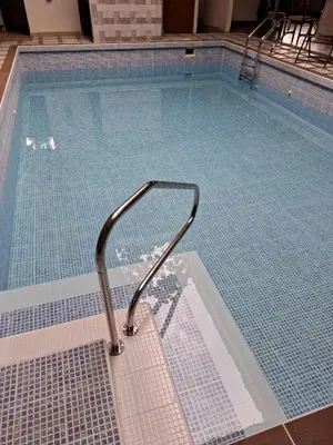 a swimming pool with a hand rail in the water at Hotel San Rafael Ecolodge in San Gerardo