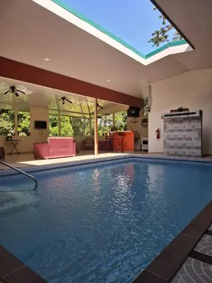 a large swimming pool in a house with a large window at Hotel San Rafael Ecolodge in San Gerardo