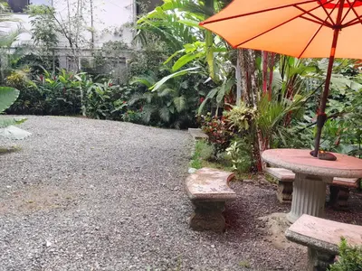 an orange umbrella sitting on a table with two benches at Casas Guaney, full furnished studios! in Manuel Antonio
