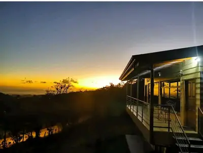 a house with the sunset in the background at Monteluna Studios Monteverde in Monteverde Costa Rica