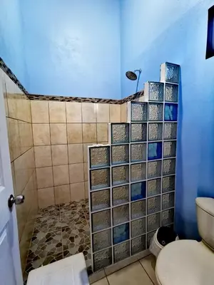 a bathroom with a shower with a toilet and a blue wall at Monteluna Studios Monteverde in Monteverde Costa Rica