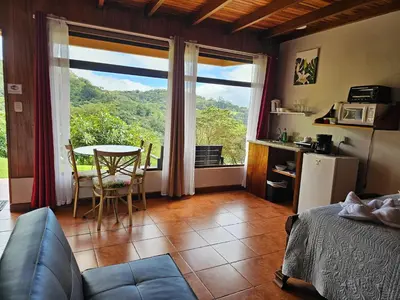 a room with a bed and a table and a window at Monteluna Studios Monteverde in Monteverde Costa Rica