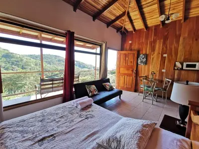 a bedroom with a large bed and a large window at Monteluna Studios Monteverde in Monteverde Costa Rica