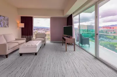 a living room with a couch and a tv and a large window at Sheraton San Jose Hotel, Costa Rica in San José