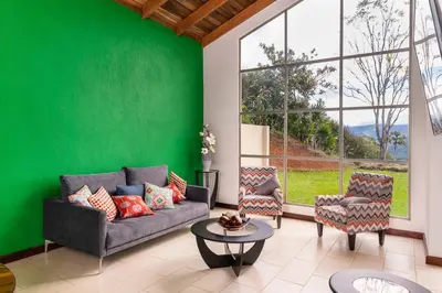 a living room with a couch and chairs and a green wall at Casa Sofia, a Gem Close to Orosi Thermal Pools! in Orosí