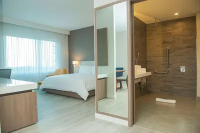 a bedroom with a bed and a bathroom with a shower at Hilton Garden Inn Santa Ana, San Jose in San José