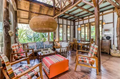 a living room with wooden furniture and a large ceiling at El Ballenato de Bahia in Uvita