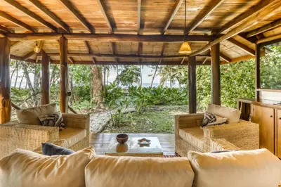 an outdoor living room with couches and a wooden pergola at El Ballenato de Bahia #2 in Uvita