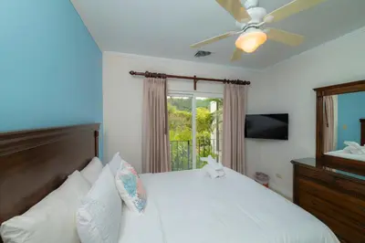 a bedroom with a bed with a ceiling fan and a window at Del Mar 3C 3 bdr Ocean View in Los Suenos in Herradura