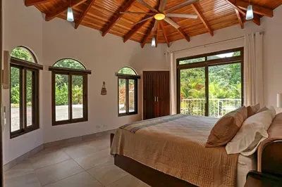 a bedroom with a large bed and windows at Stunning Casa de la Roca House with Infinity Pool! in Ojochal