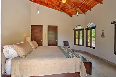 a bedroom with a large bed in a room with windows at Stunning Casa de la Roca House with Infinity Pool! in Ojochal