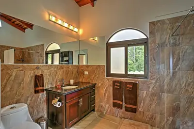 a bathroom with a sink and a toilet and a window at Stunning Casa de la Roca House with Infinity Pool! in Ojochal