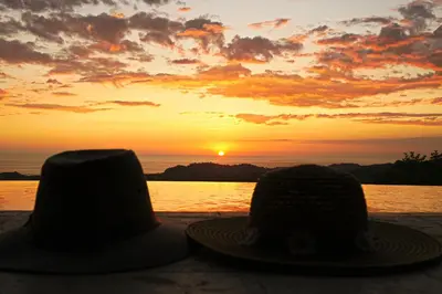 two hats sitting on a table in front of a sunset at Stunning Casa de la Roca House with Infinity Pool! in Ojochal