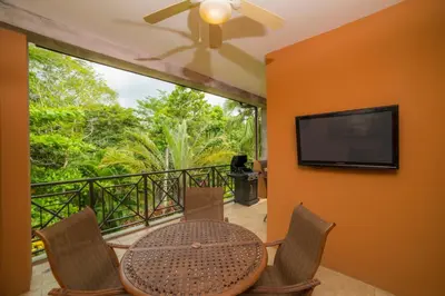a balcony with a table and chairs and a flat screen tv at Veranda 1C 3 bdr Golf Course View in Los Suenos in Herradura