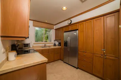 a kitchen with wooden cabinets and a stainless steel refrigerator at Veranda 1C 3 bdr Golf Course View in Los Suenos in Herradura