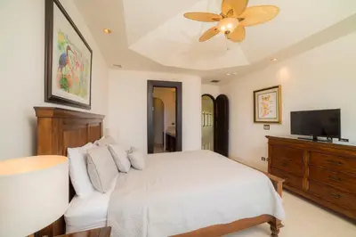 a bedroom with a white bed and a ceiling fan at Puesta del Sol 5 bdrs ocean view in Los Suenos in Herradura