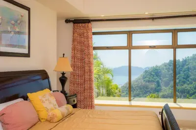 a bedroom with a bed and a large window with a view at Puesta del Sol 5 bdrs ocean view in Los Suenos in Herradura