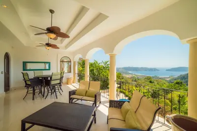 a living room with a balcony with a table and chairs at Puesta del Sol 5 bdrs ocean view in Los Suenos in Herradura
