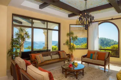 a living room filled with furniture and large windows at Puesta del Sol 5 bdrs ocean view in Los Suenos in Herradura