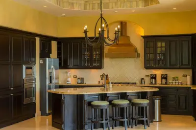 a kitchen with black cabinets and a island with bar stools at Puesta del Sol 5 bdrs ocean view in Los Suenos in Herradura