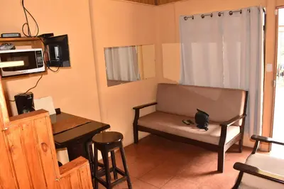 a living room with a chair and a table and a microwave at Casa con vista a valle de Dota y zona cafetalera in Santa María