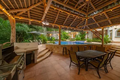 a patio with a table and chairs and a swimming pool at Harmon Estate 6 bdrs private pool in Los Suenos in Herradura