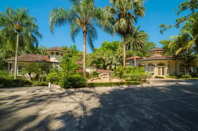 a house with palm trees in front of a driveway at Harmon Estate 6 bdrs private pool in Los Suenos in Herradura