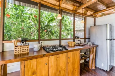 a kitchen with wooden cabinets and a large window at El Ballenato de Bahia Whole House in Uvita