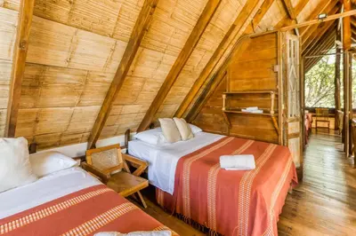 a bedroom with two beds in a wooden cabin at El Ballenato de Bahia Whole House in Uvita