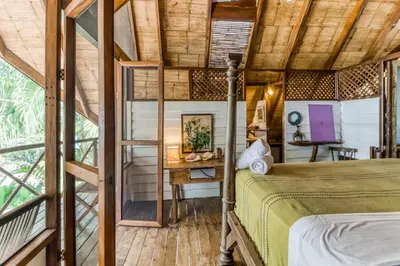 a bedroom in a tree house with a bed and a desk at El Ballenato de Bahia Whole House in Uvita