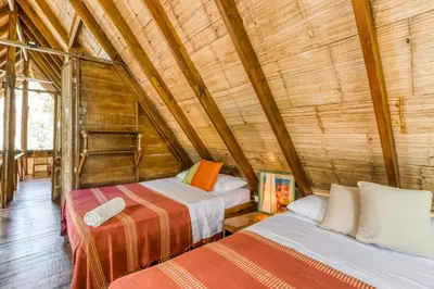a room with two beds in a wooden house at El Ballenato de Bahia Whole House in Uvita