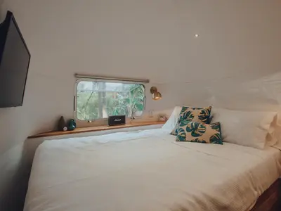 a bedroom with a large white bed with a window at Airstream by the Sea in Nosara