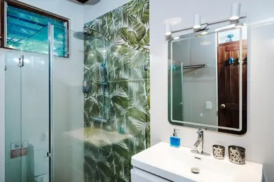 a bathroom with a shower and a sink and a mirror at Casa Sueca Hotel - At the Beach in Tamarindo