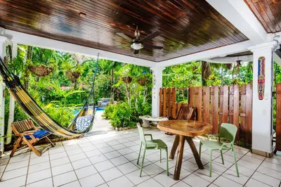 a porch with a hammock and a table and chairs at Casa Sueca Hotel - At the Beach in Tamarindo