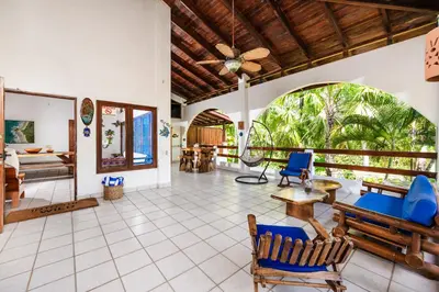 a living room with a ceiling fan and blue chairs at Casa Sueca Hotel - At the Beach in Tamarindo